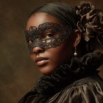 A woman wearing a dark lace mask and Renaissance inspired clothing looks over her shoulder against a muted background