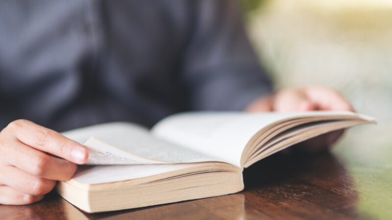 A person turns a page in an open paperback book